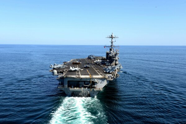 An American aircraft carrier is moving through the blue sea