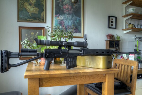 A weapon with an optical sight in a room with paintings on the walls