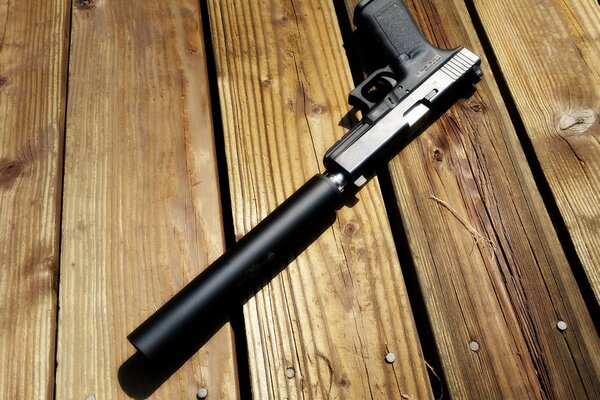 Pistol with a silencer on a wooden surface