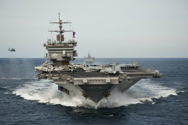 The aircraft carrier dissects the expanses of the ocean, waiting for the helicopter to land