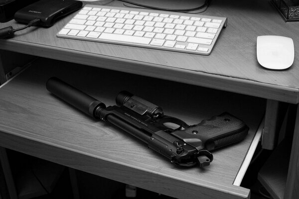 Пистолет с глушителем на полке в столе