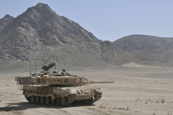 Serbatoio di battaglia nel deserto sullo sfondo della montagna