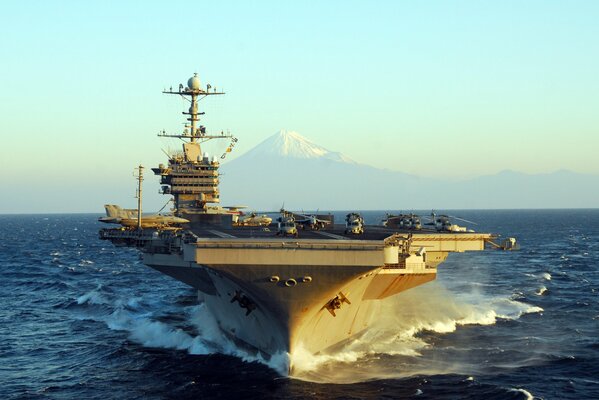 Un porte-avions de type Nimitz dissèque les vagues sur le fond d un sommet de montagne