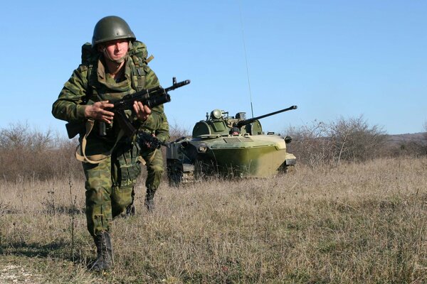 Militär läuft mit Maschinengewehr über das Feld