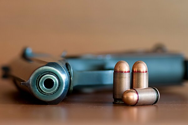 A pistol and three cartridges on the table