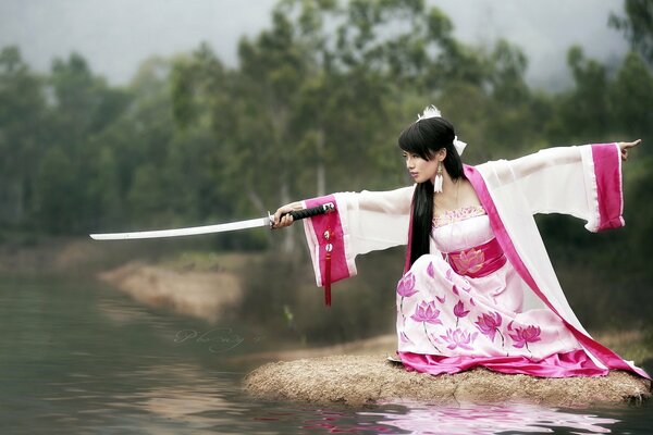 A girl with a katana on the river bank