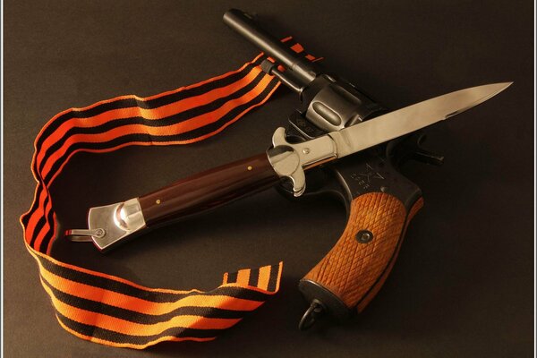 A crossed folding knife and a pistol with a wooden handle are framed with a St. George ribbon