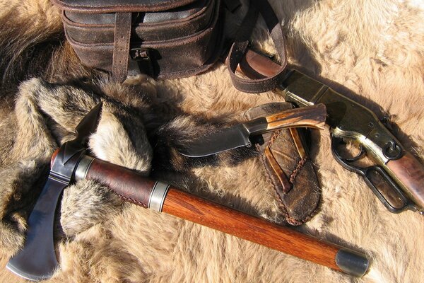 Knife, axe, tomahawk and rifle lying on the fur