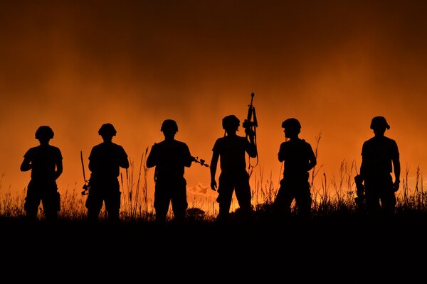 Soldaten mit Waffen bei Sonnenuntergang im Gras