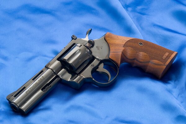 A revolver with a wooden handle lying on a blue cloth