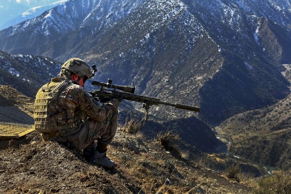 Sniper militaire en camouflage visant dans les montagnes