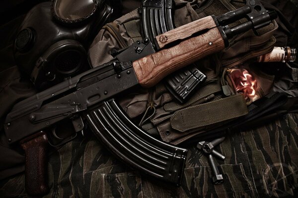 AK-47 assault rifle with a clip on the background of camouflage and a gas mask