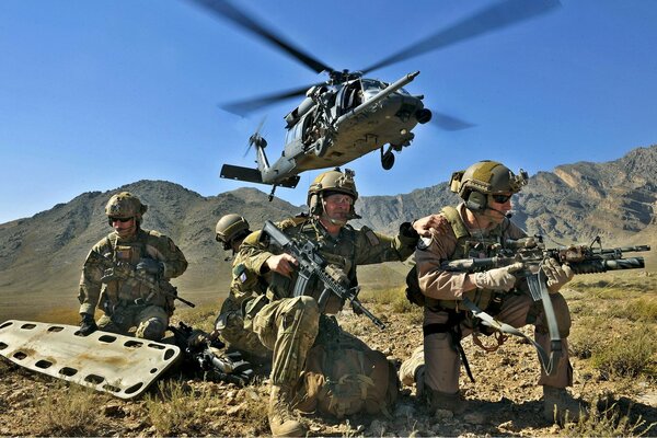 Soldats avec des civières et des armes sous un hélicoptère