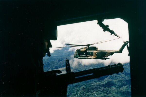 Ein Soldat im Hubschrauber, ein anderes Flugzeug fliegt dagegen