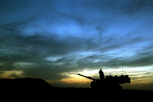 The service is going on at night. a soldier on a tank