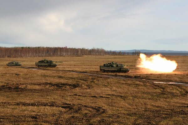 Three tanks are driving across the field