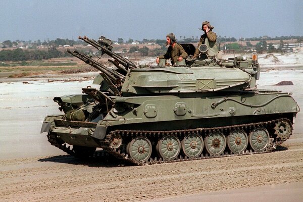 A tank with people is driving along the road