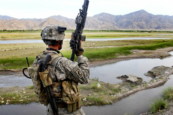 A soldier with a gun enjoys mountain views