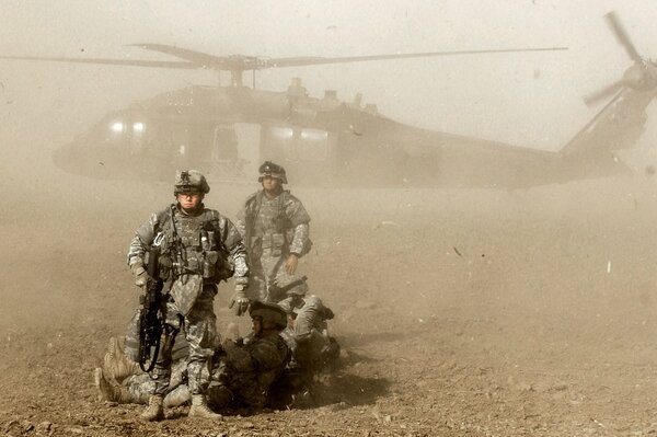 Soldiers in front of the helicopter in the dust