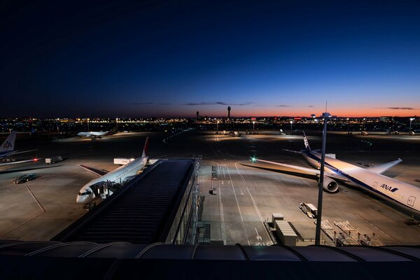 Пассажирские самолёты в аэропорту на фоне ночного города