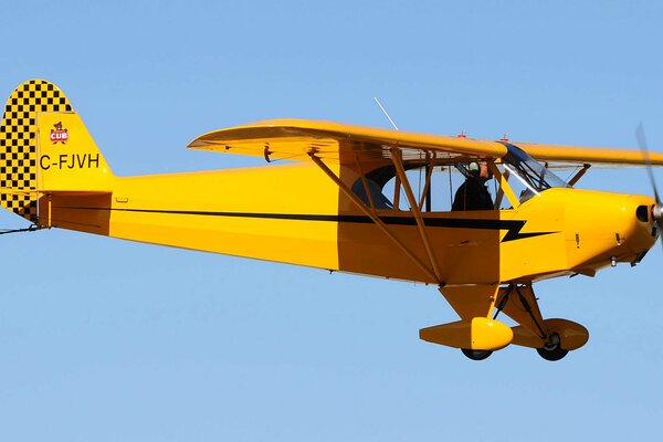 Pilot im klaren Himmel auf einem gelben Retro-Flugzeug