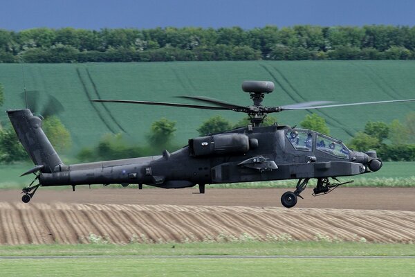 Apache ah-64 helicopter flies over fields