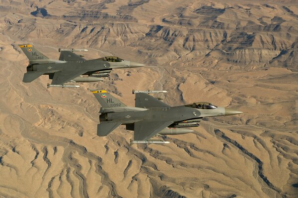 Zwei f-16 Fighting falcon fliegen vor Wüstenhintergrund