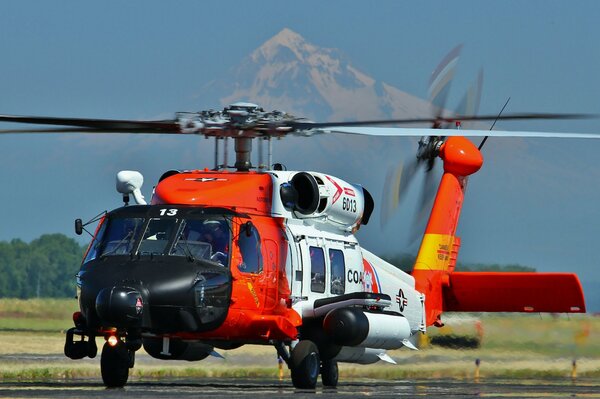 Helicóptero despega en el aeródromo en medio de una montaña