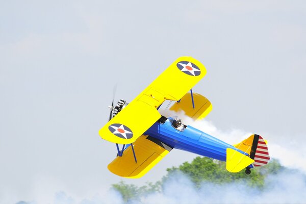 Yellow-blue biplane flying in the fog