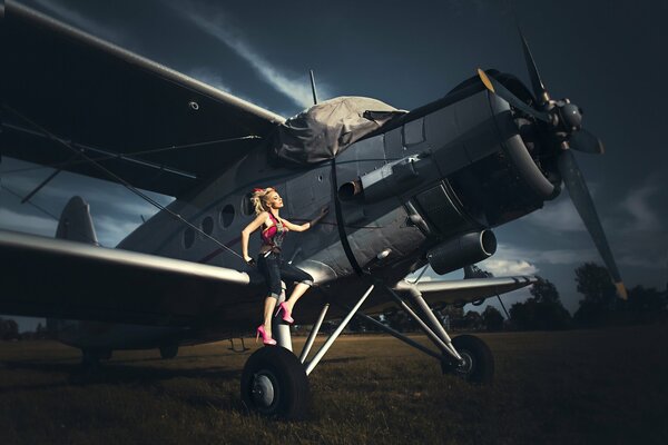 A huge biplane plane in the field and a girl model