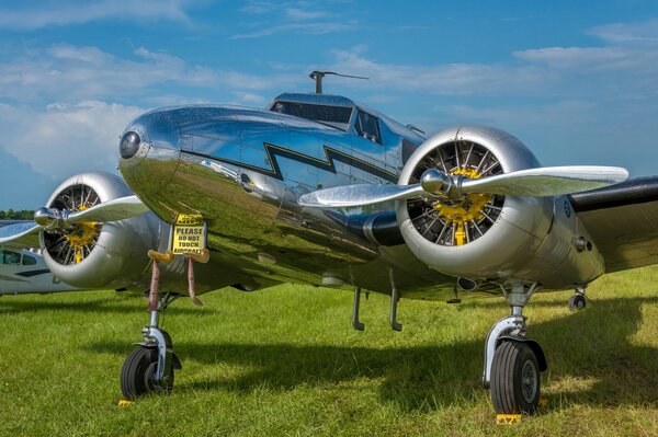 Flugzeug auf dem Hintergrund des klaren Himmels auf dem Gras