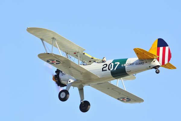 The US Coast Guard biplane plane flies in the blue sky