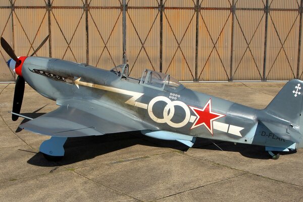 A painted Soviet Yak-3 fighter stands in a hangar