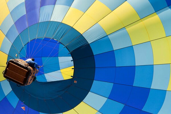 A multicolored balloon takes off with people in a basket