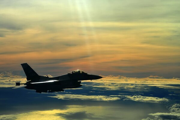 A military fighter among the clouds at sunset