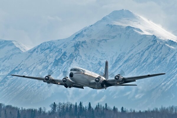 Military transport plane in the sky on the background of a snow-covered mountain