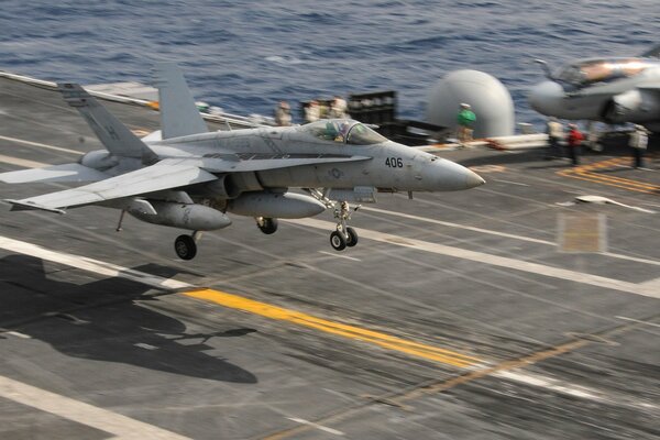 A military plane lands on the deck of an aircraft carrier