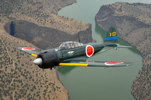 A military fighter flies over the river