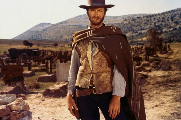 On the prairie among grave crosses and sand stands Clint Eastwood, a frame of the film