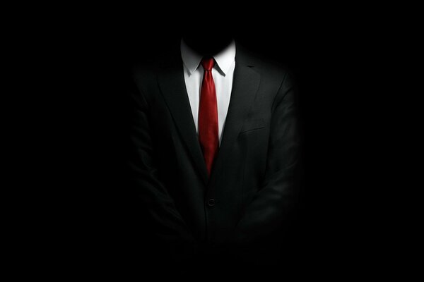 A shirt with a red tie under a black suit that merged with the background