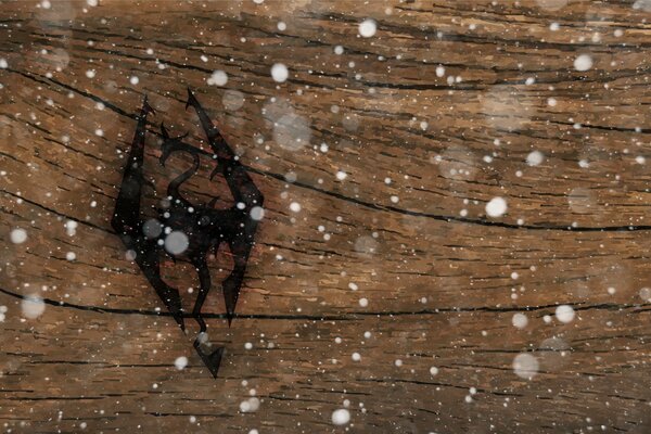 Logo gry komputerowej Skyrim naniesione na powierzchnię drewna