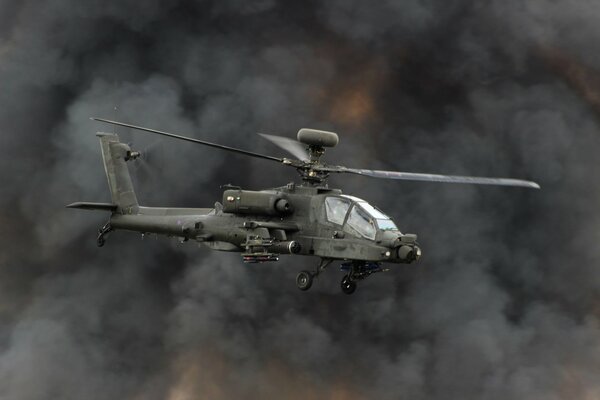 A helicopter gunship flies in the smoke from the explosions