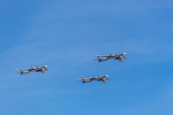 Three military planes fly against the blue sky