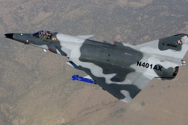 A camouflaged fighter in the sky over a mountainous area