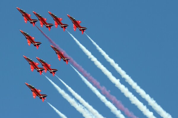 Exhibición aérea de nueve aviones con flecha roja