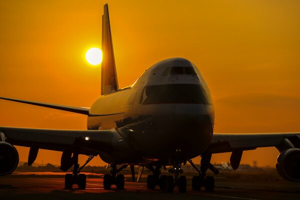 Passagierflugzeug Boeing-747a im Hintergrund des Sonnenuntergangs