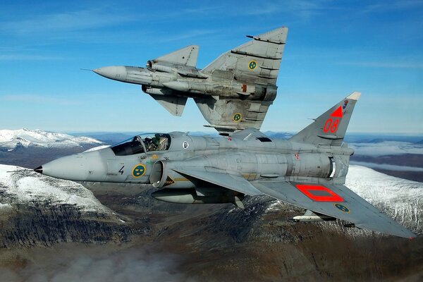 Two fighter jets fly over the mountains