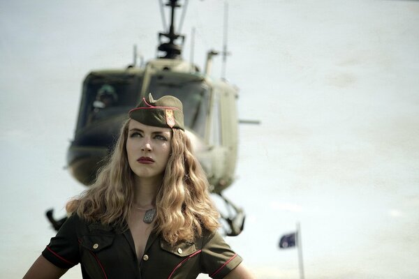 Bella ragazza sotto forma di un pilota davanti a un elicottero