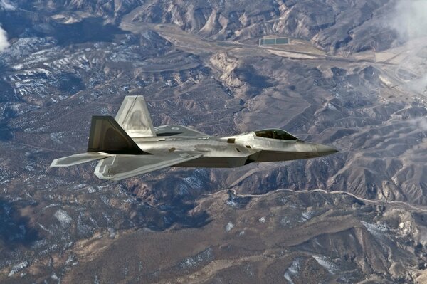 A multi-purpose fighter is flying over the mountains