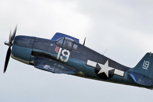 A small fighter is flying in a gray sky